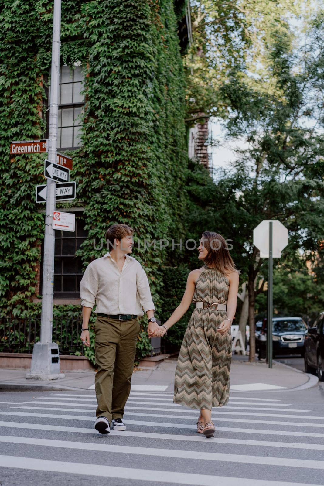 A romantic couple walks hand in hand, savoring the beautiful moments they share in a lush, ivycovered street