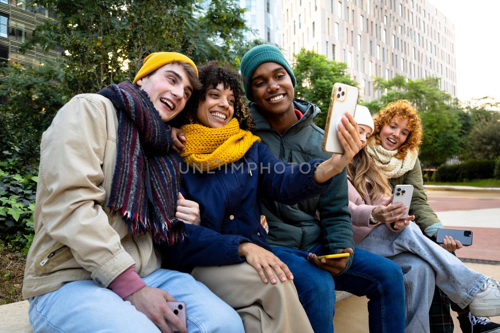 Happy multiracial group of smiling and cheerful college student friends taking selfie together in a winter day using mobile phone. Technology and lifestyle concept.