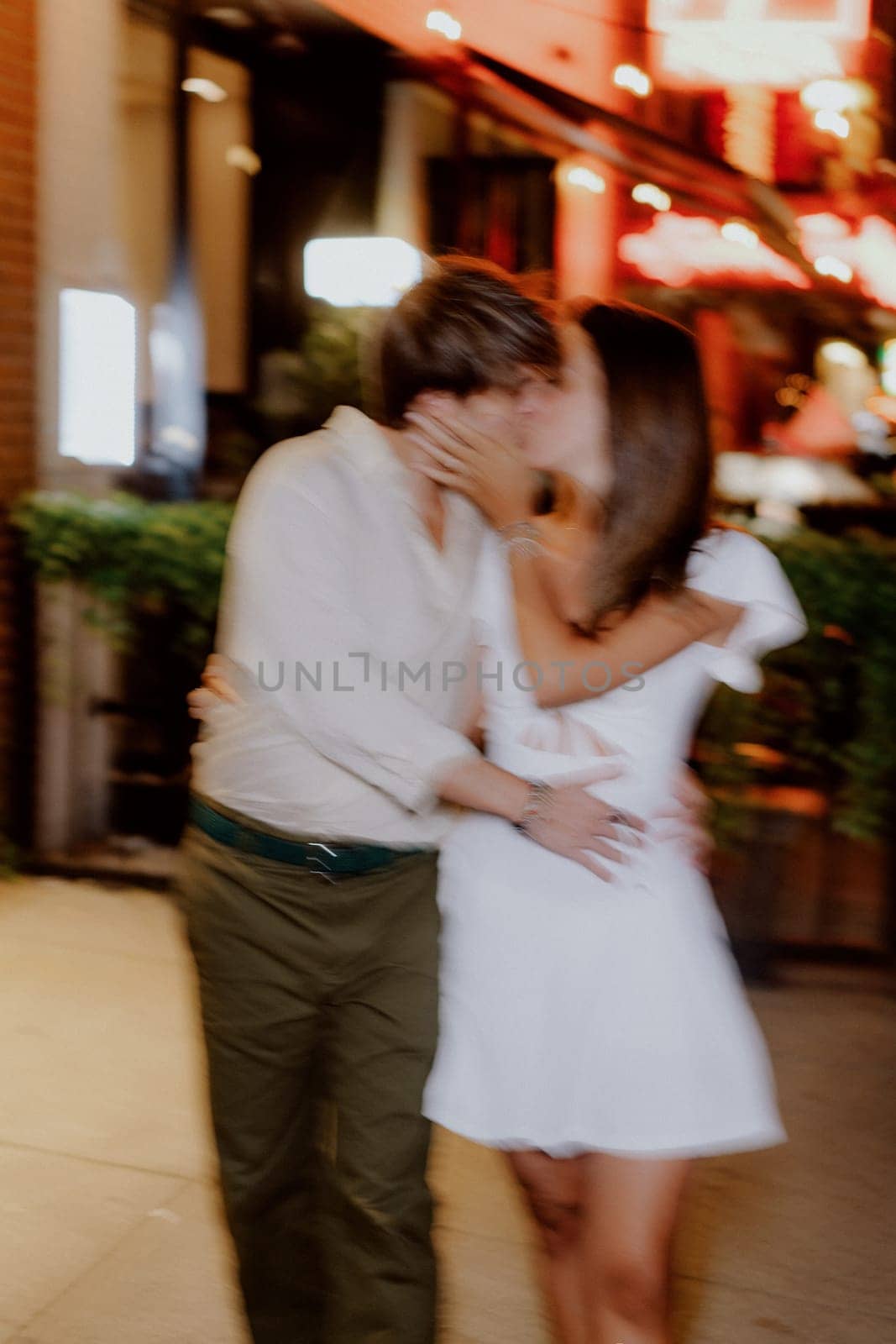 A couple happily enjoying a romantic and intimate walk together at night, dressed in stylish casual clothing