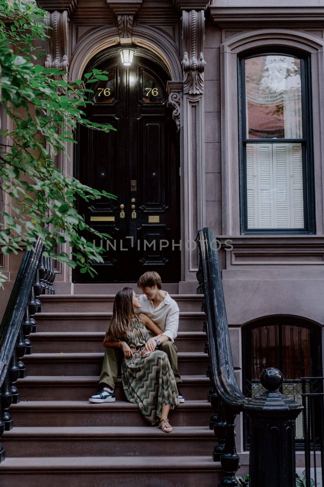 A couple shares a peaceful and quiet moment together on the steps of a charming urban brownstone building