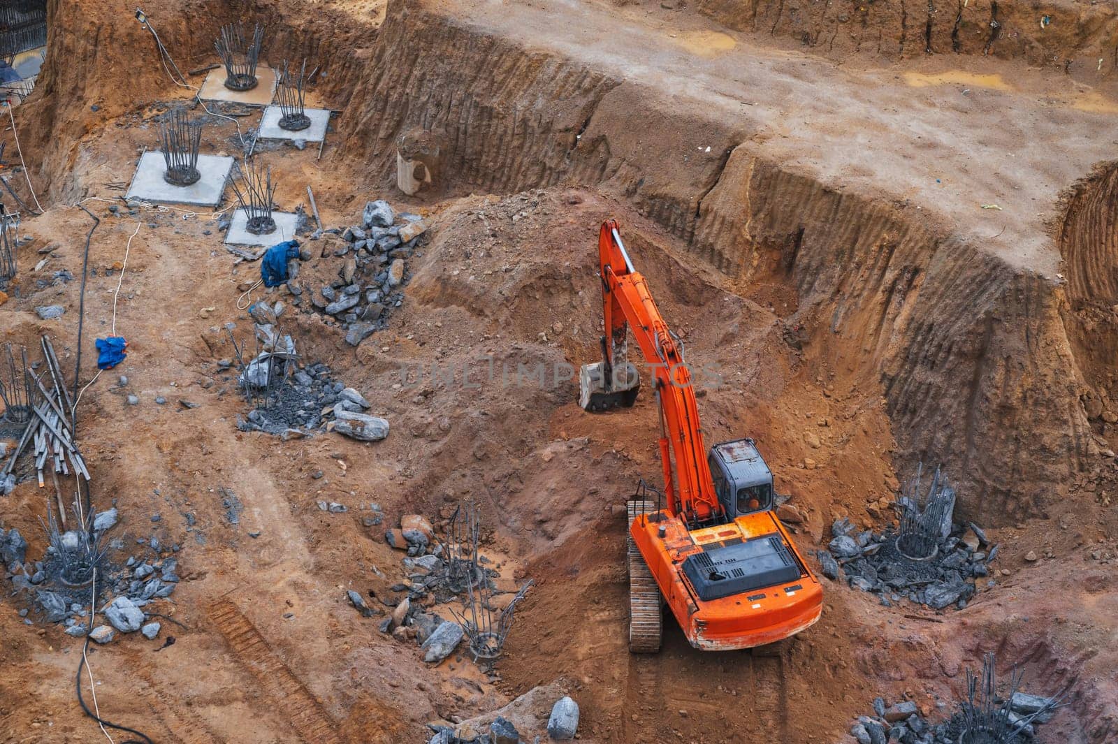 excavator digs the ground under the foundation pit at a construction site