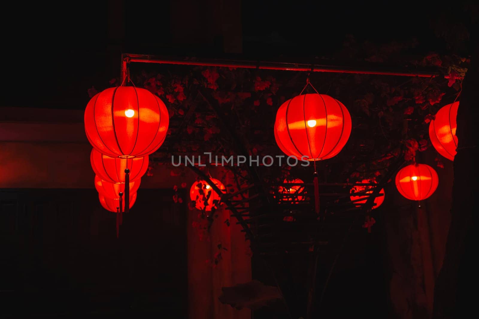 red traditional paper Chinese lanterns decorate the facade of a building in Asia at night