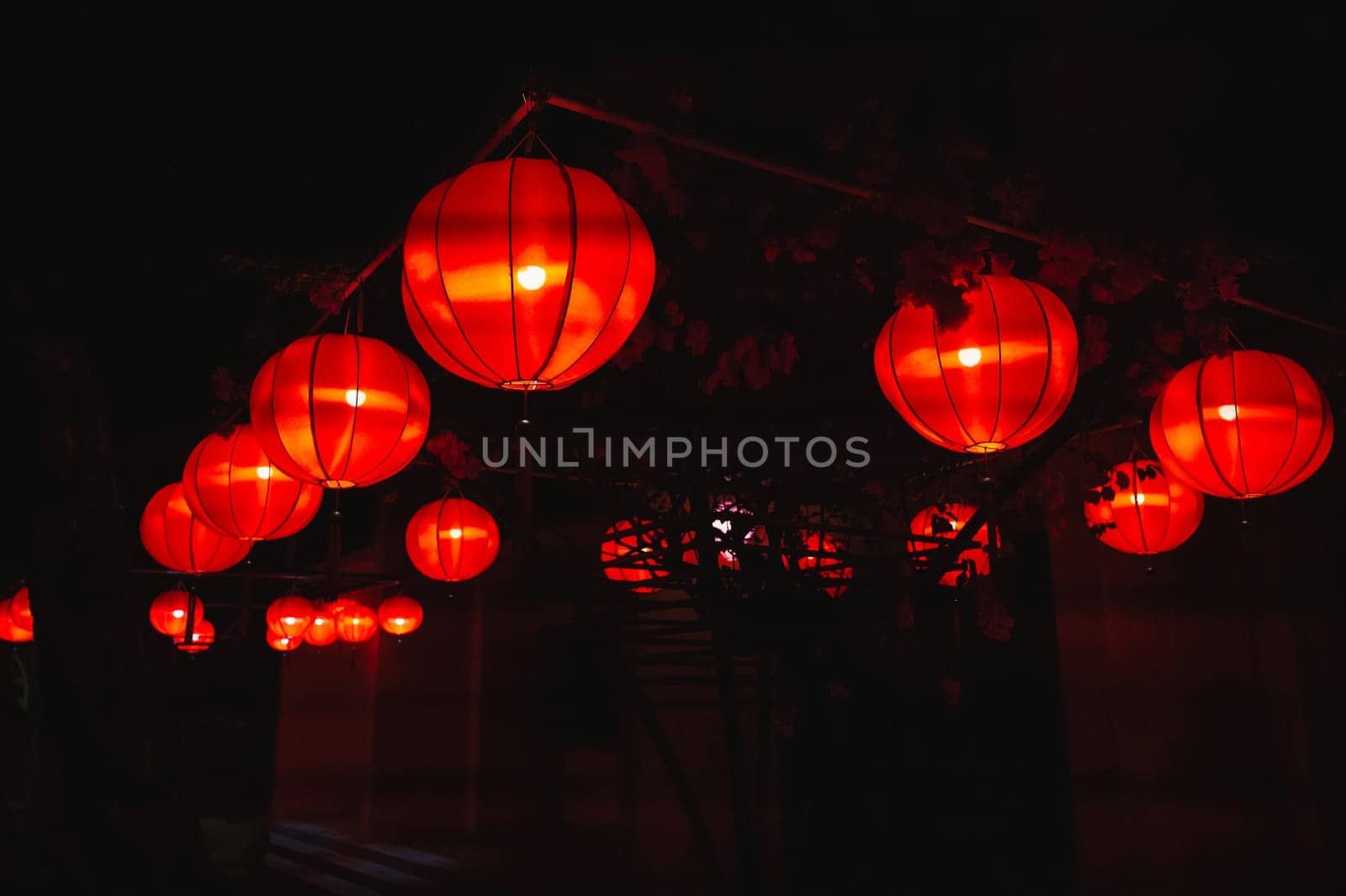 Glowing red traditional paper Chinese lanterns decorate the facade of a building in Asia at night
