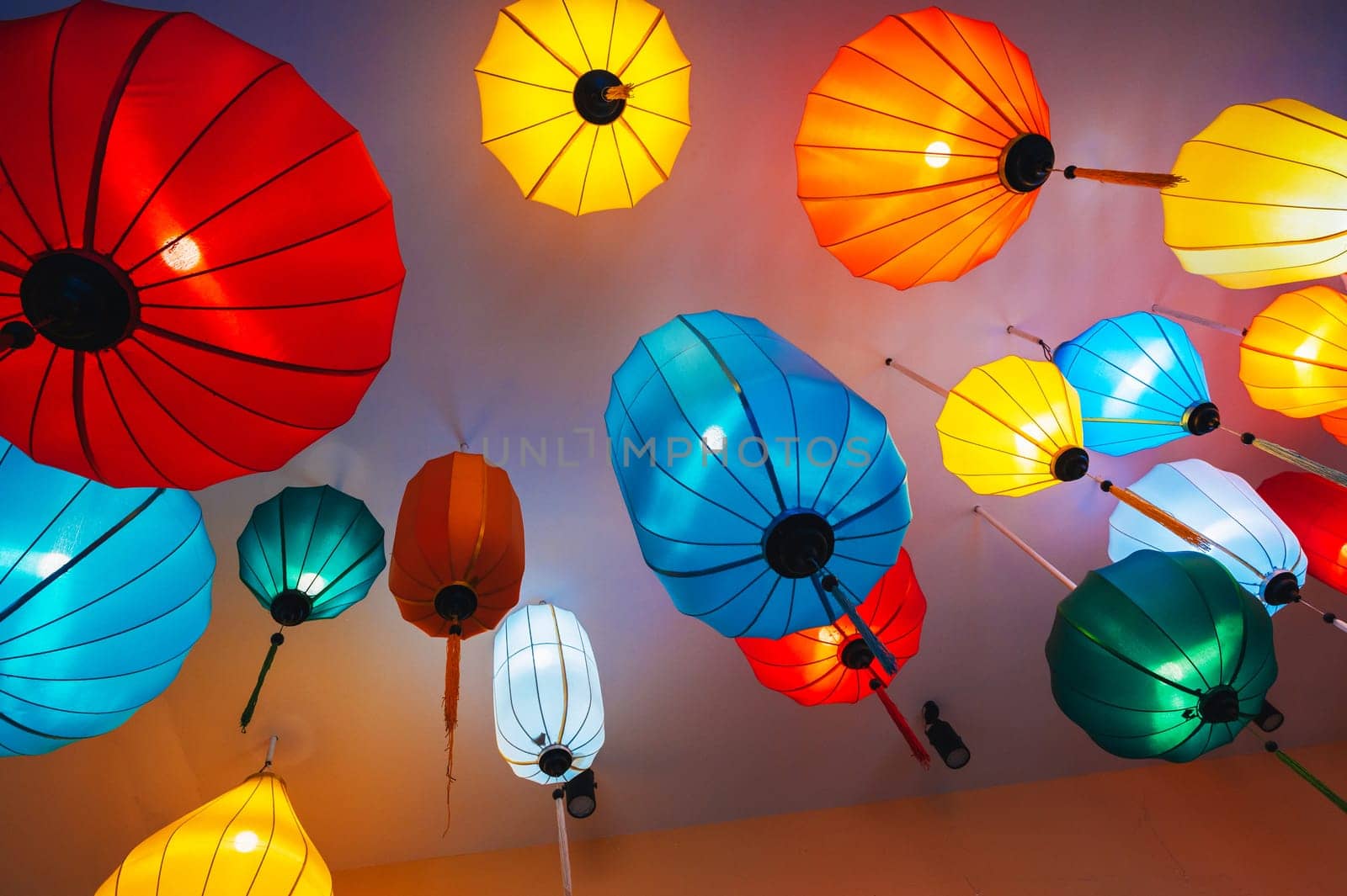 Traditional colorful silk hanging Chinese lanterns in the ceiling of an Asian cafe for interior decoration
