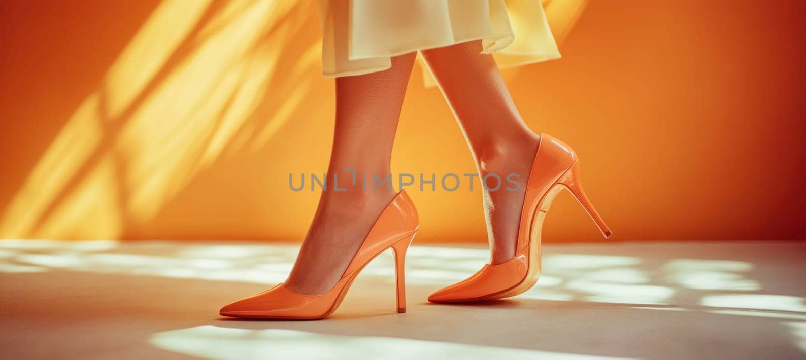 Elegant woman's legs wearing stylish orange high heel shoes, walking gracefully on a white floor against an orange backdrop