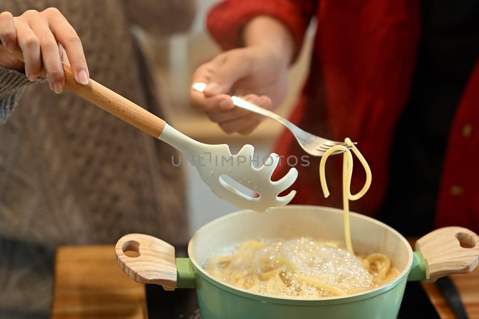 Young married couple preparing delicious pasta on Christmas Day.