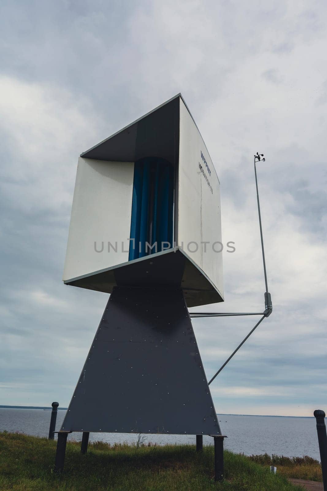 A modern coastal lookout tower with a minimalist, geometric design stands against an overcast sky, showcasing contemporary architecture and abstract lines in a scenic coastal setting