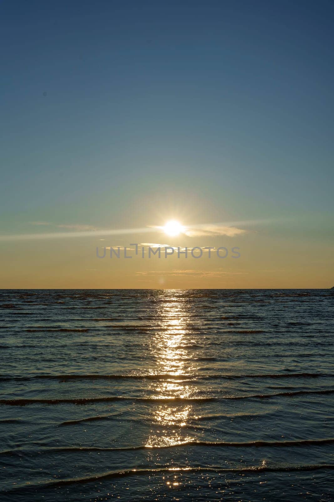 A peaceful sunset over a calm ocean with gentle waves and a colorful sky, creating a tranquil and scenic landscape. The image captures the beauty of twilight with no people in view.