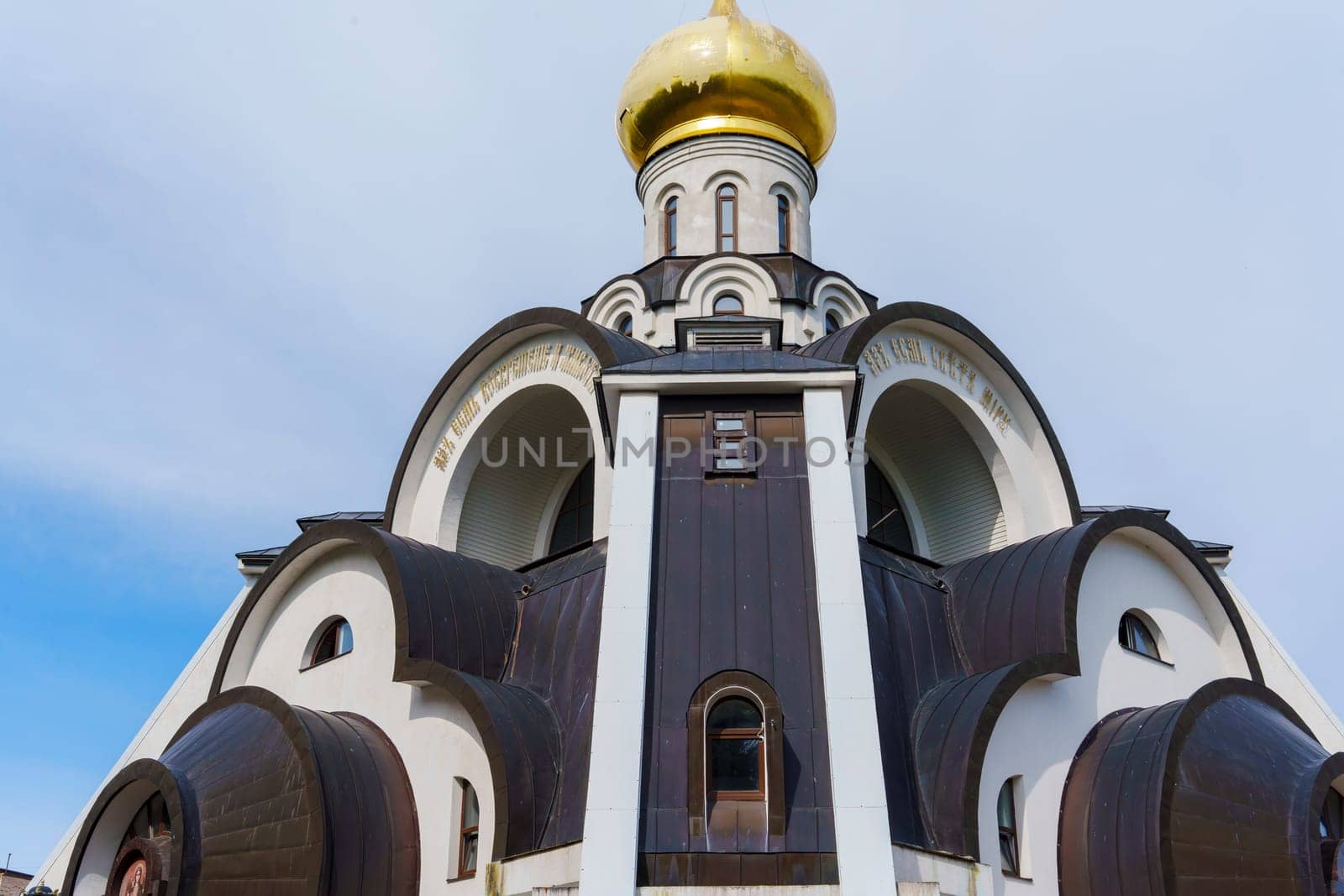 Ornate Orthodox church with a golden dome and intricate arched architectural details, symbolizing Eastern Orthodox tradition against a soft sky