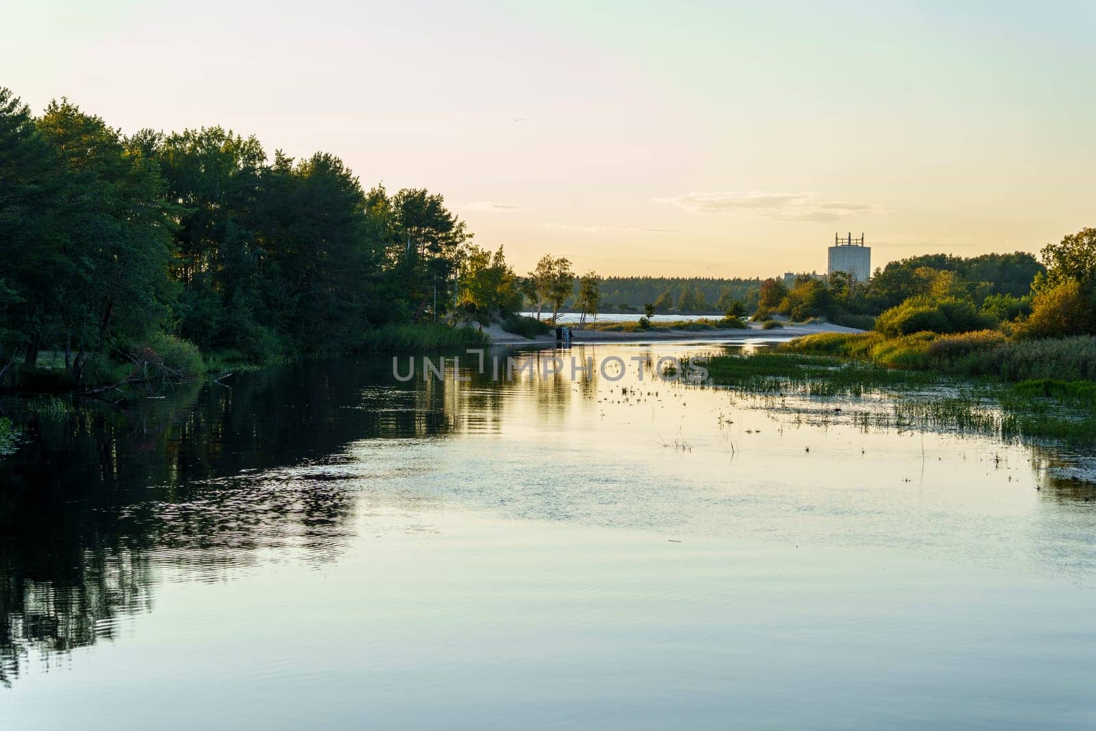 Calm river flowing through a lush landscape with trees lining the banks, soft sunset light creating reflections on the water, and a distant bridge enhancing the scenic view