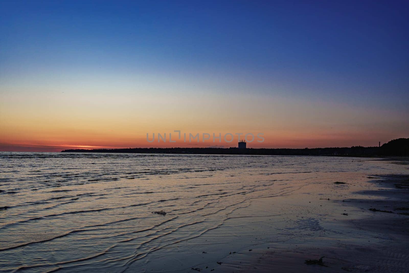 Serene beach scene at sunset with gentle waves and a calm horizon, creating a peaceful atmosphere with soft twilight colors reflecting on the wate