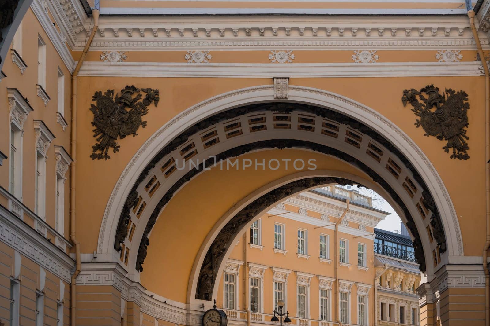 Ornate archway framing the view of historic buildings on a clear day, showcasing classical architectural design and urban elegance in a European cityscape