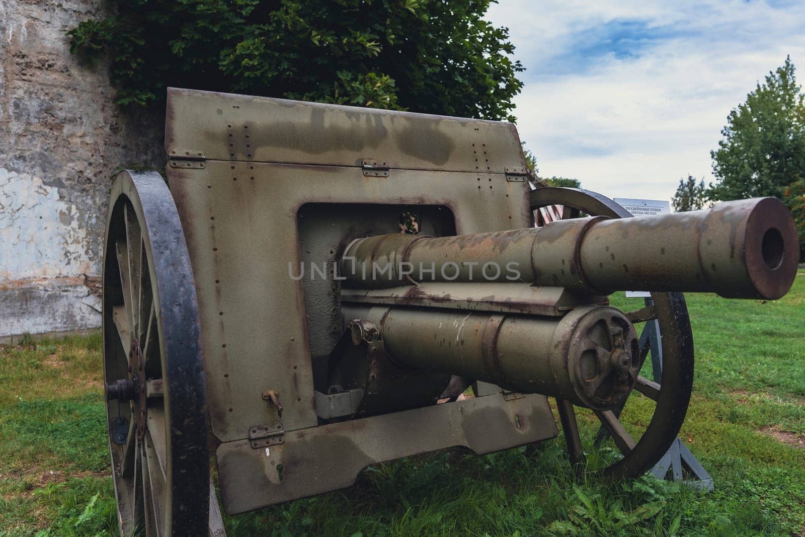 An antique military cannon with rusted metal parts, displayed outdoors on a green field, highlighting its historical significance and aged appearance as a relic of military history