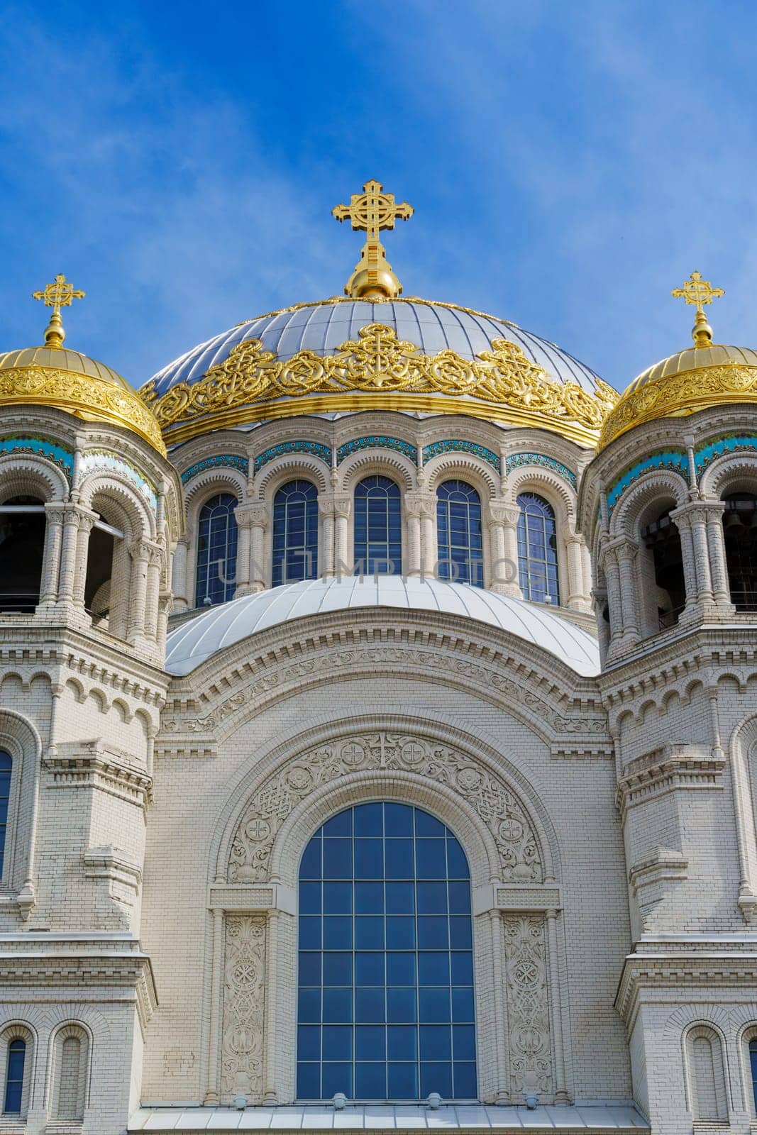 A grand cathedral with prominent golden domes and an ornate facade, displaying intricate architectural details under a bright blue sky, symbolizing cultural and spiritual heritage