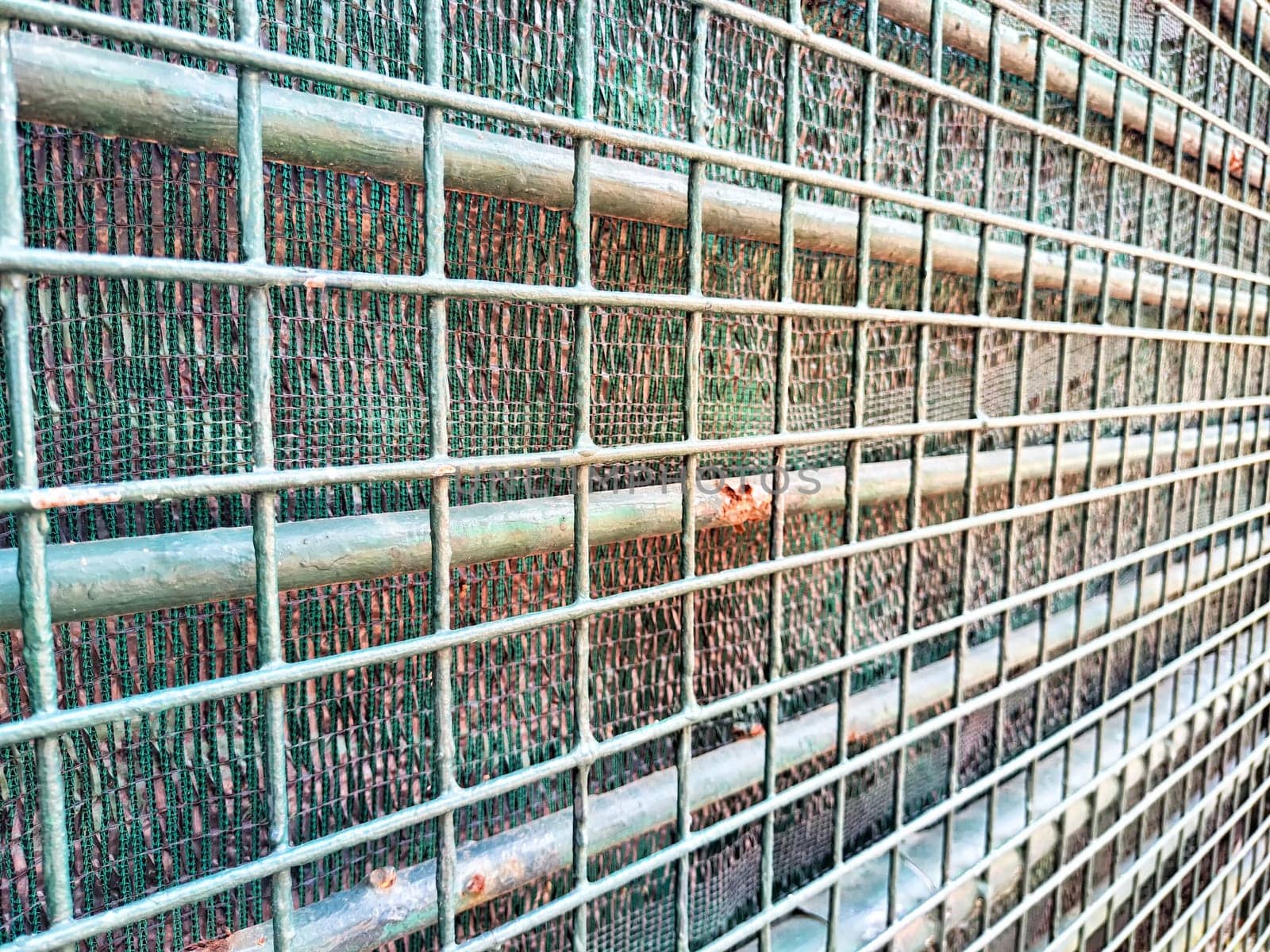 A close-up view of a metal grid fence showing horizontal bars and mesh elements.