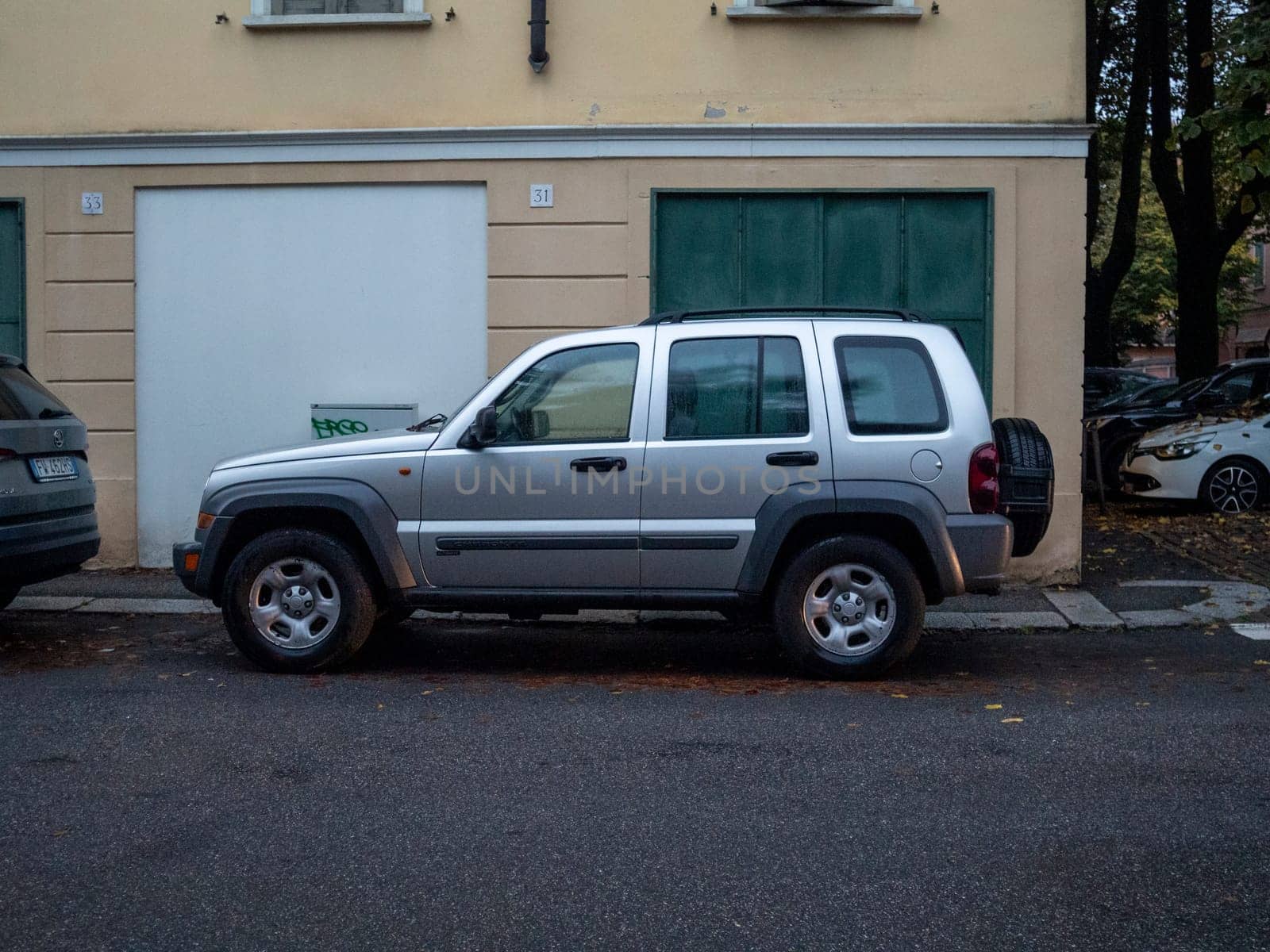 Cremona, Lombardy, Italy October 15th 2024 Silver jeep liberty parked on a quiet residential street in autumn, showcasing urban parking and automotive lifestyle