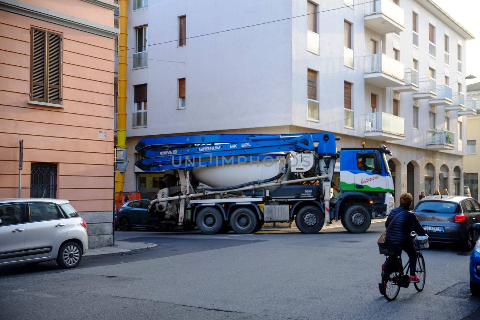 Cremona, Lombardy, Italy - November 7th 2024 Concrete mixer truck driving on a street in a residential area, passing a cyclist