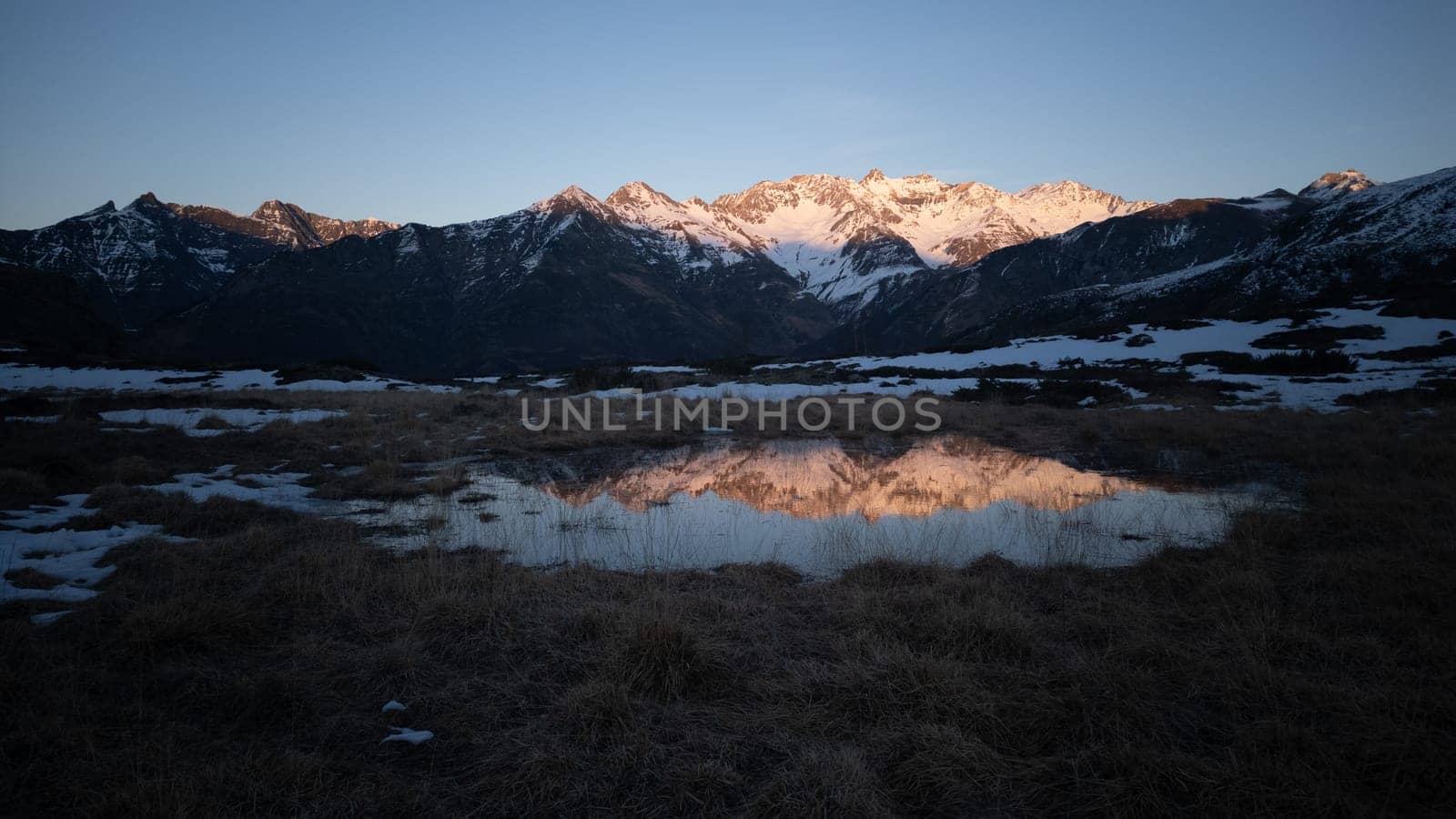 Sunset over the Pyrenees mountains with the reflection of the peaks in the water of the lake High quality 4k footage