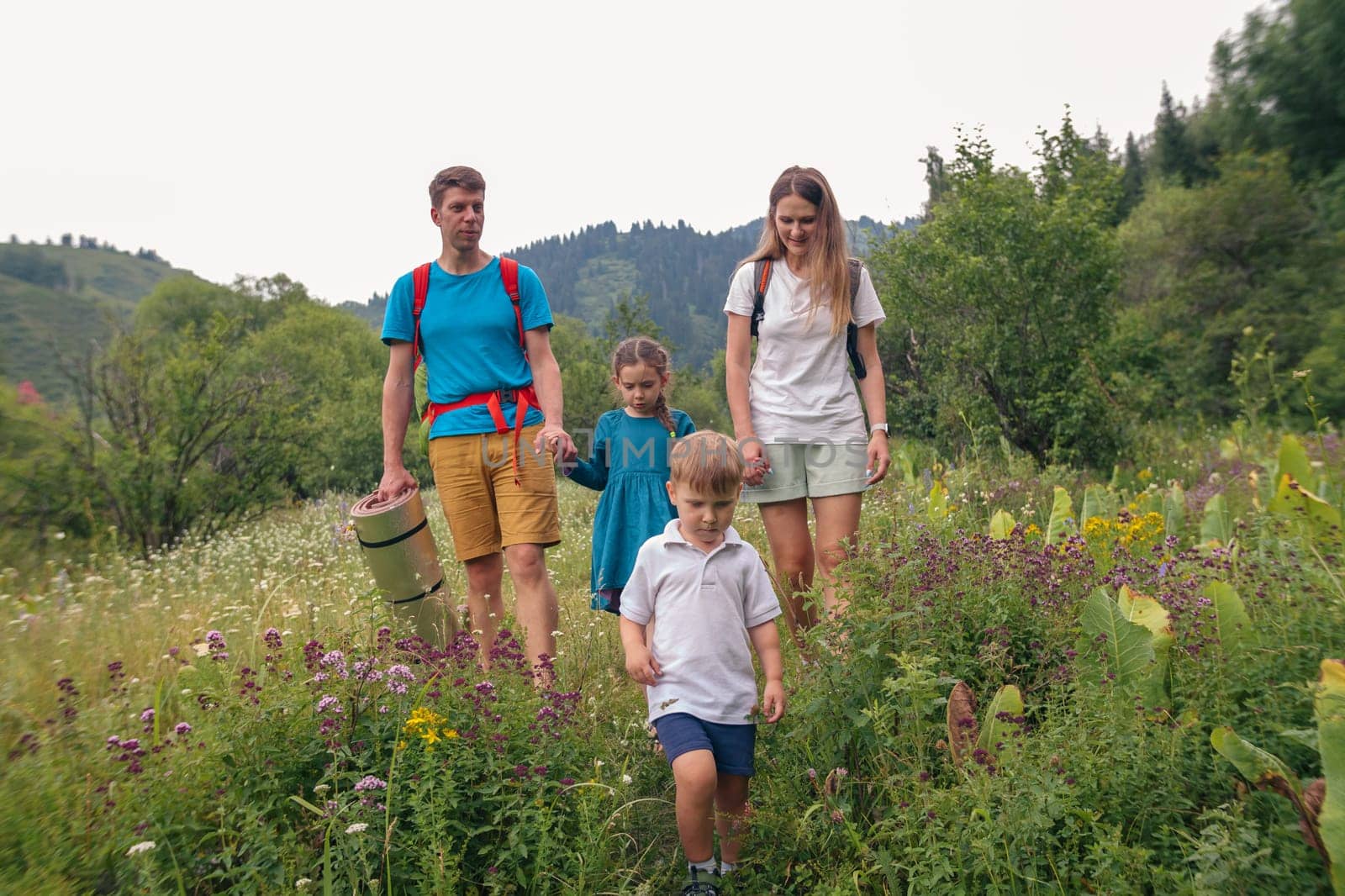 A family consisting of four members joyfully explores vibrant and colorful wildflowers during a delightful outdoor hike