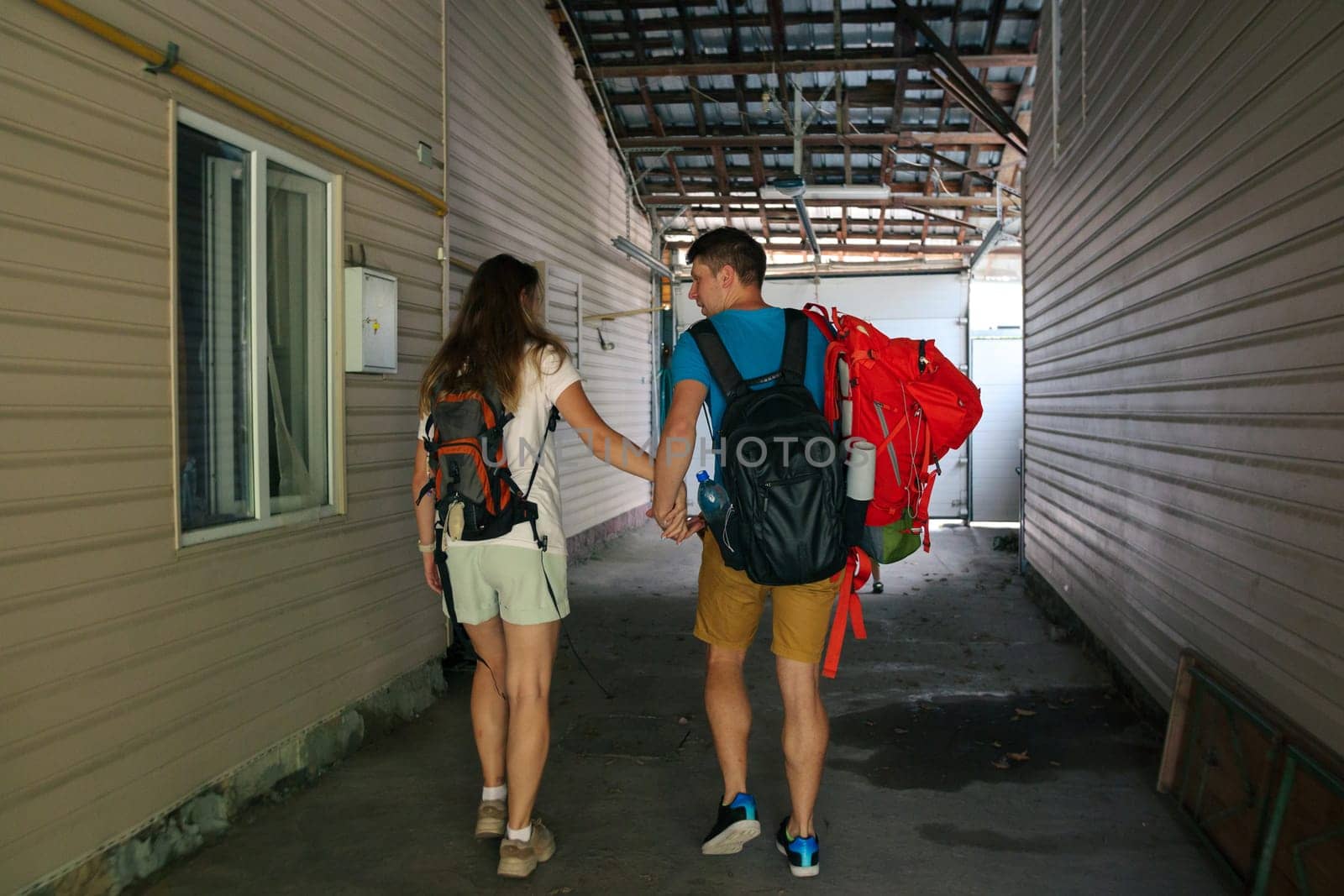 A young couple happily enjoying a precious moment together while carrying their backpacks in a cozy corridor