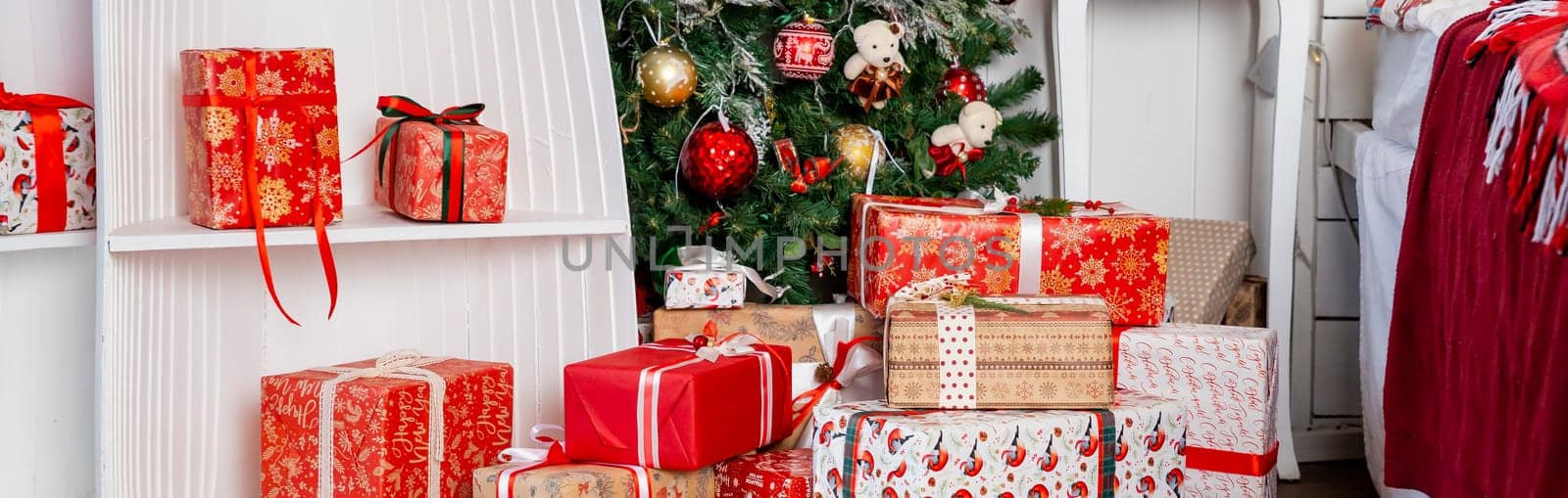 Stylish wrapped christmas gifts with ribbon on table on background of decorated christmas tree