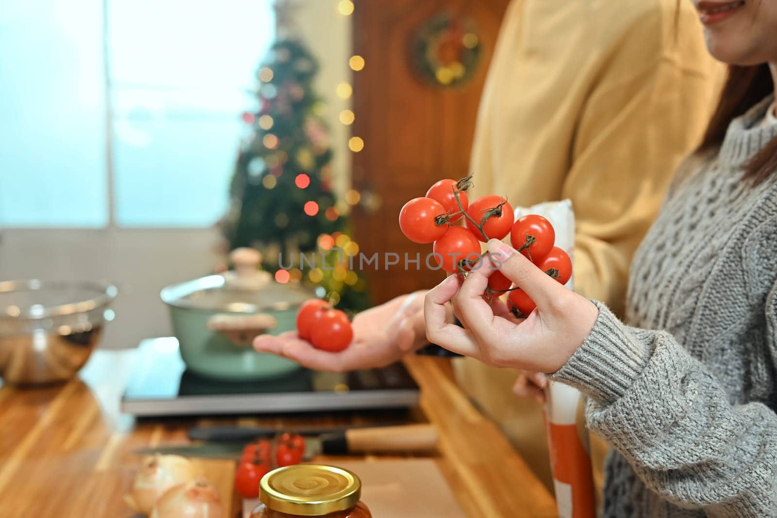 Close up of young woman choosing fresh tomatoes for a holiday dish.