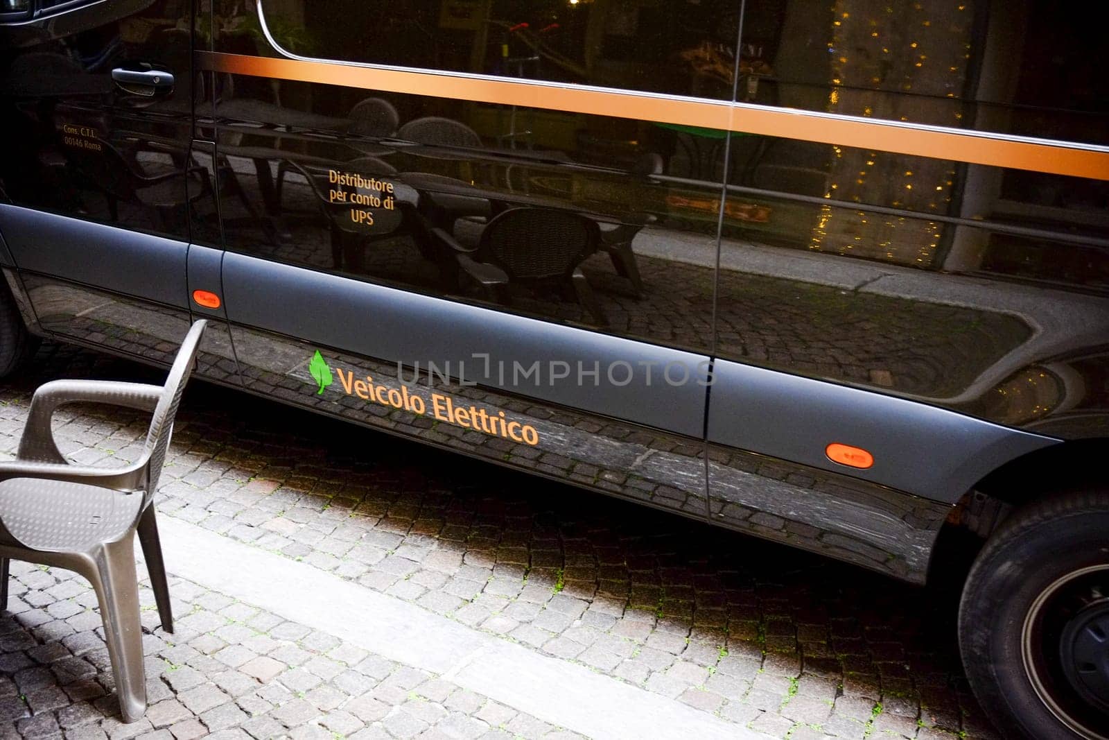 Cremona, Lombardy, Italy - November 7th 2024 Black electric van parked on a cobblestone street, operating as a delivery vehicle for ups, promoting sustainable logistics