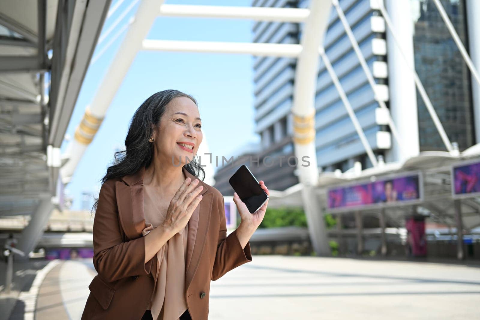 Happy mature businesswoman enjoying a conversation in front of an office building.