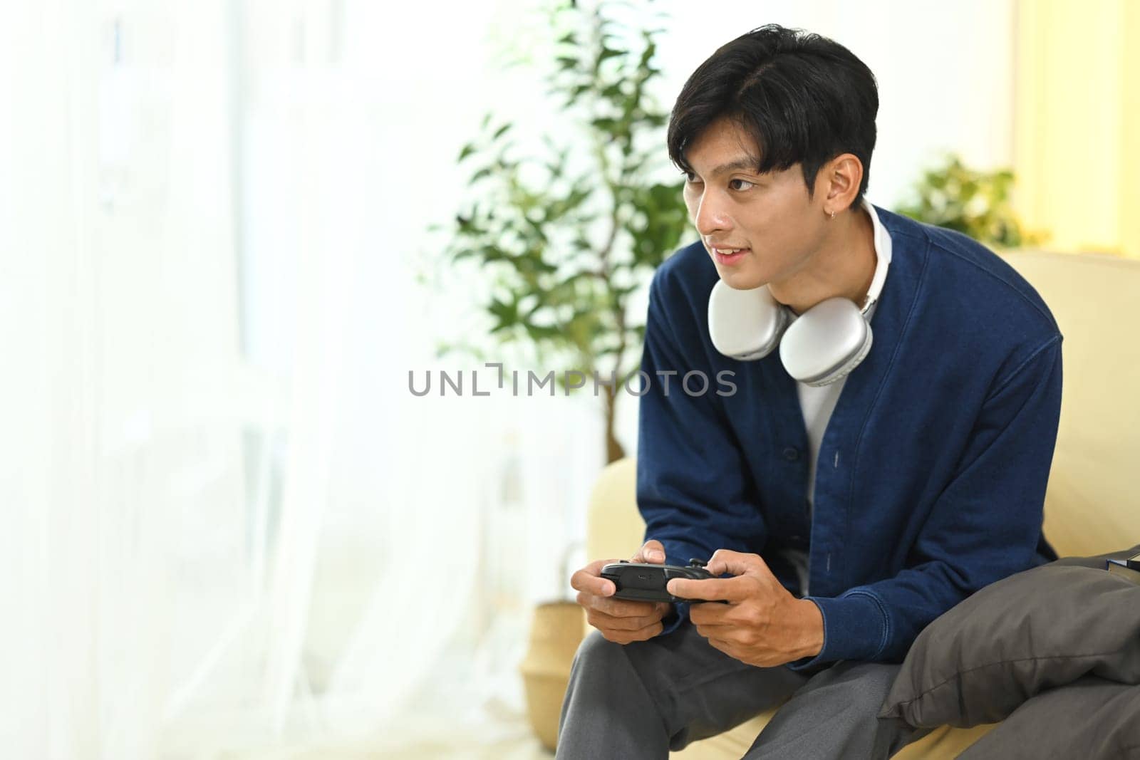 Man in casual outfit Playing video games with controller in living room.