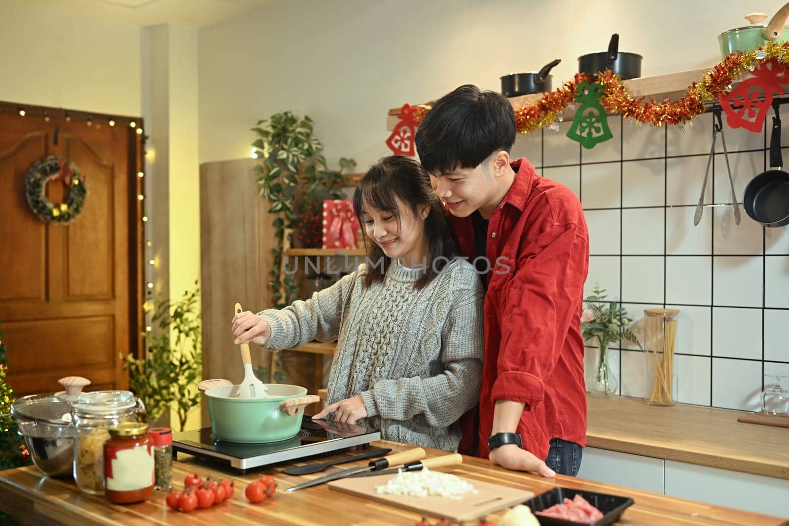 Loving couple preparing a festive meal together in a decorated kitchen.