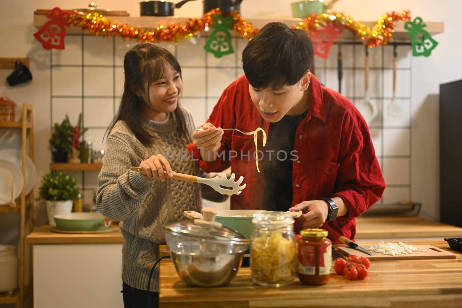 Happy couple preparing a festive meal together in a decorated kitchen.