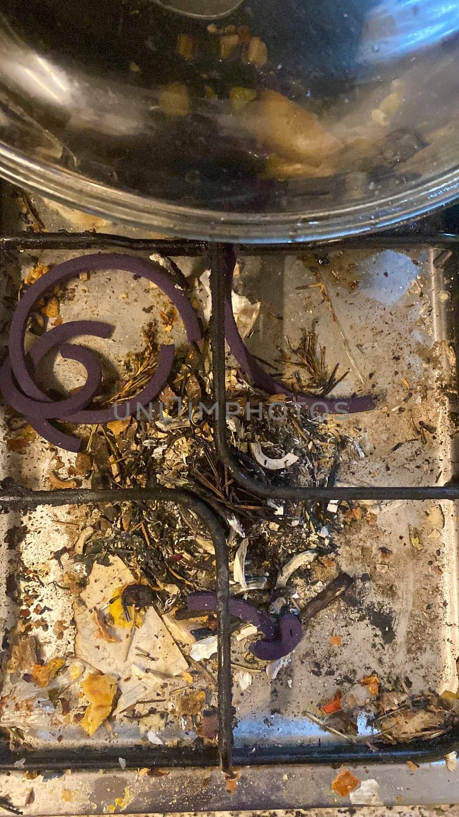 Cremona, Lombardy, Italy October 15th 2024 Food and debris covering a very dirty gas stove top with purple rubber burner covers