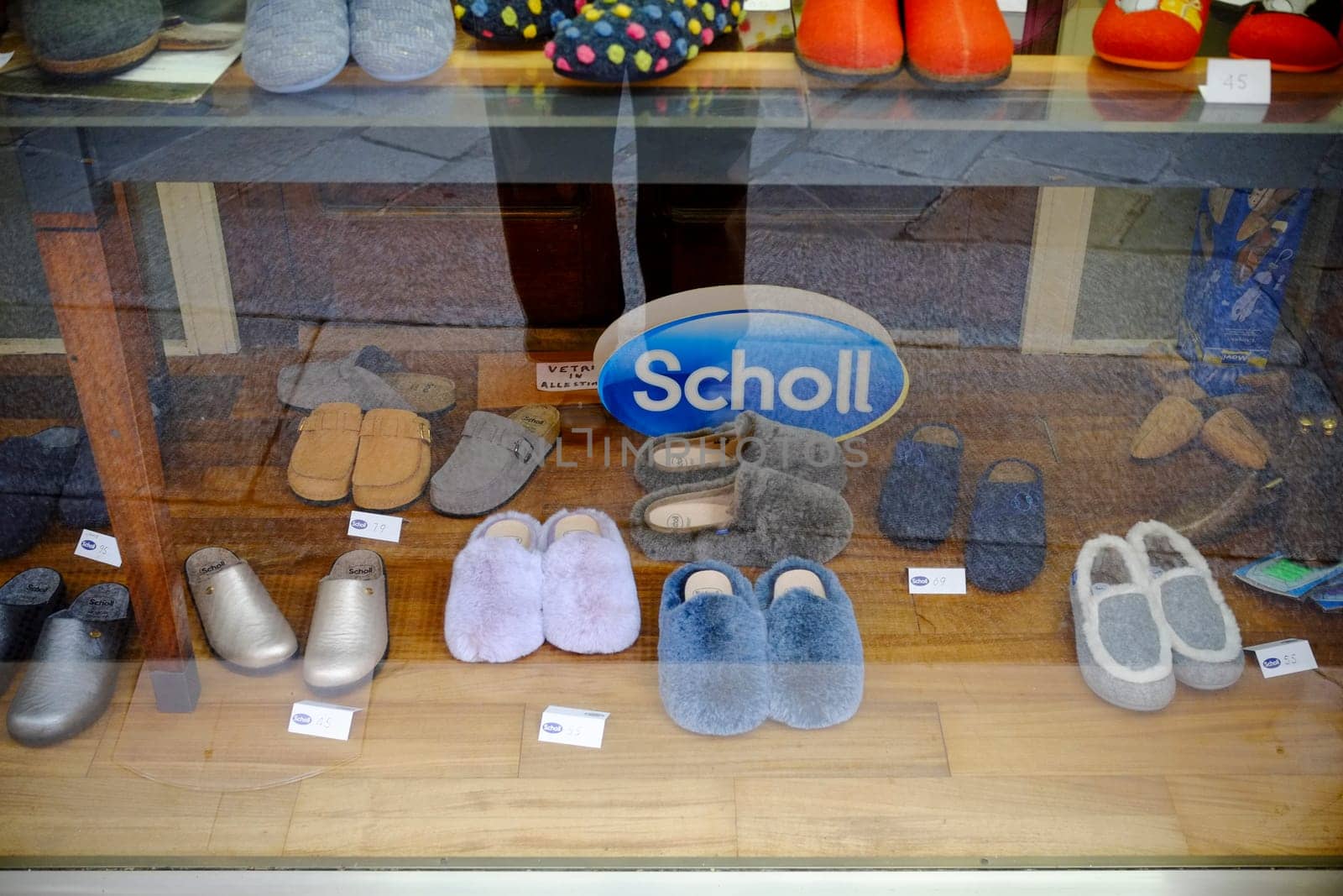 Cremona, Lombardy, Italy - November 7th 2024 Colorful and comfortable slippers are displayed for sale in a shoe store window, featuring a prominent scholl sign
