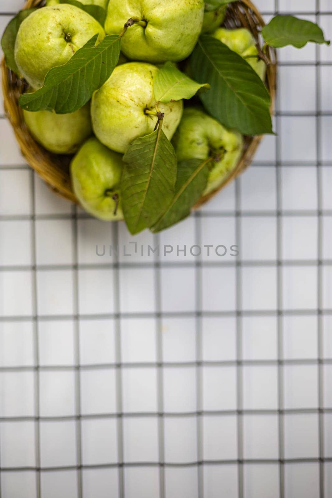 Green guava in the bamboo basket on the table.
