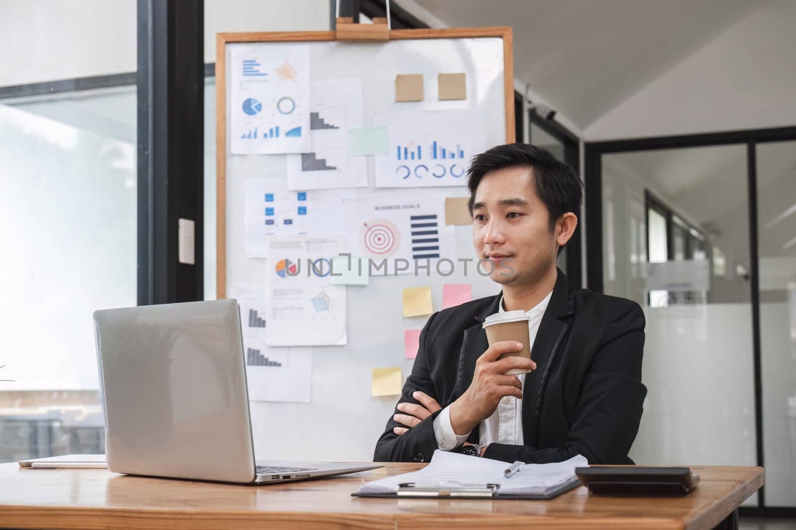 Young Asian businessman working on laptop in office by wichayada