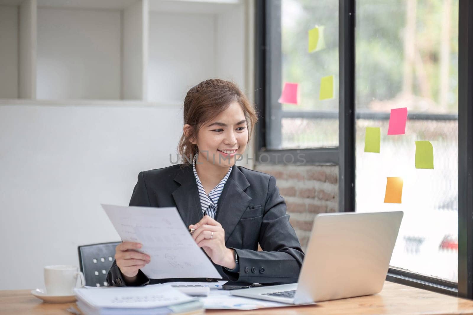 Asian businesswoman doing accounting with laptop and financial report graph in office..