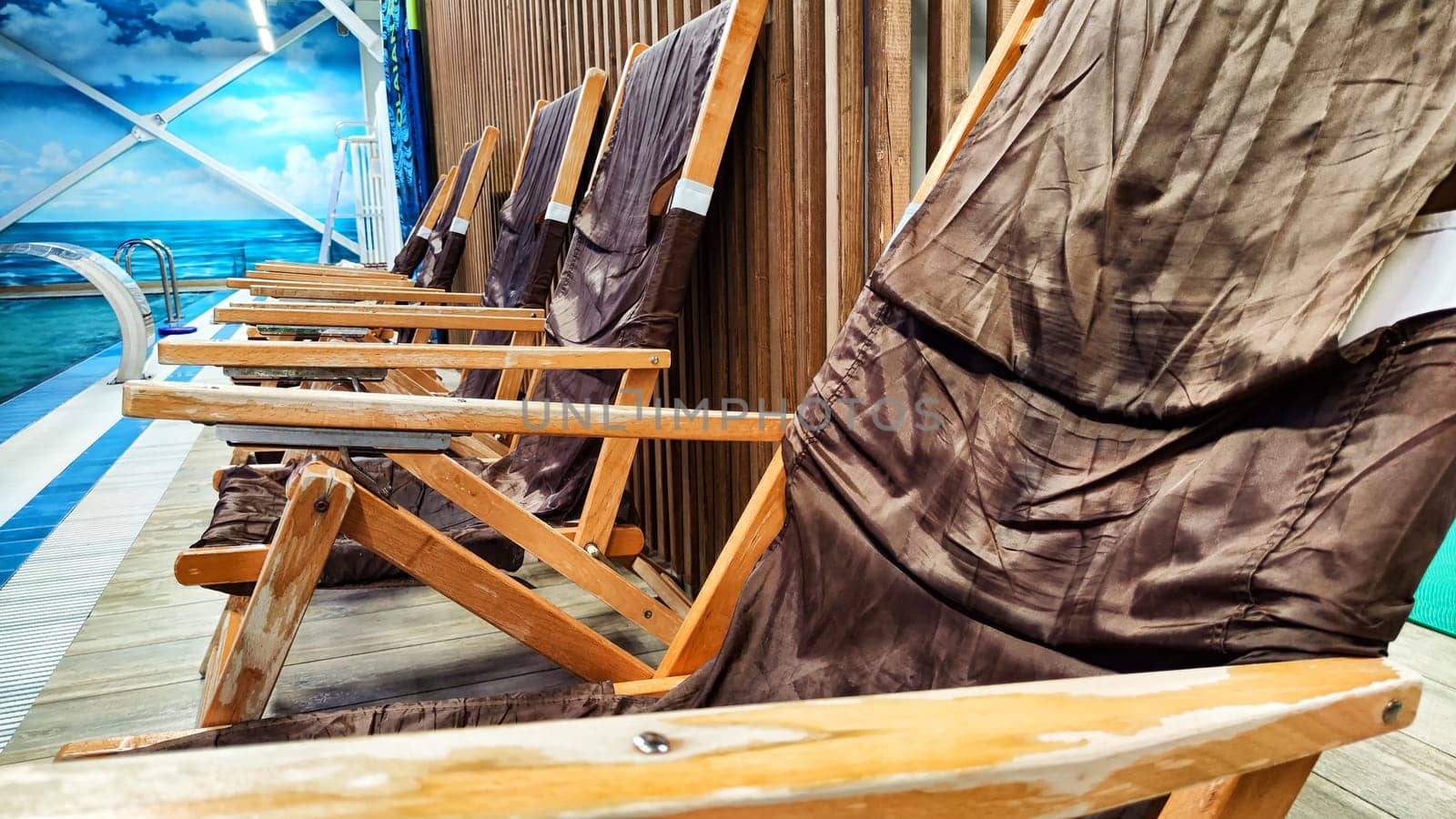 empty, brown, plastic sun loungers and covered beach umbrellas lined up next to the pool. Empty place to rest in the morning sun. The hotel is closed during the pandemic for quarantine