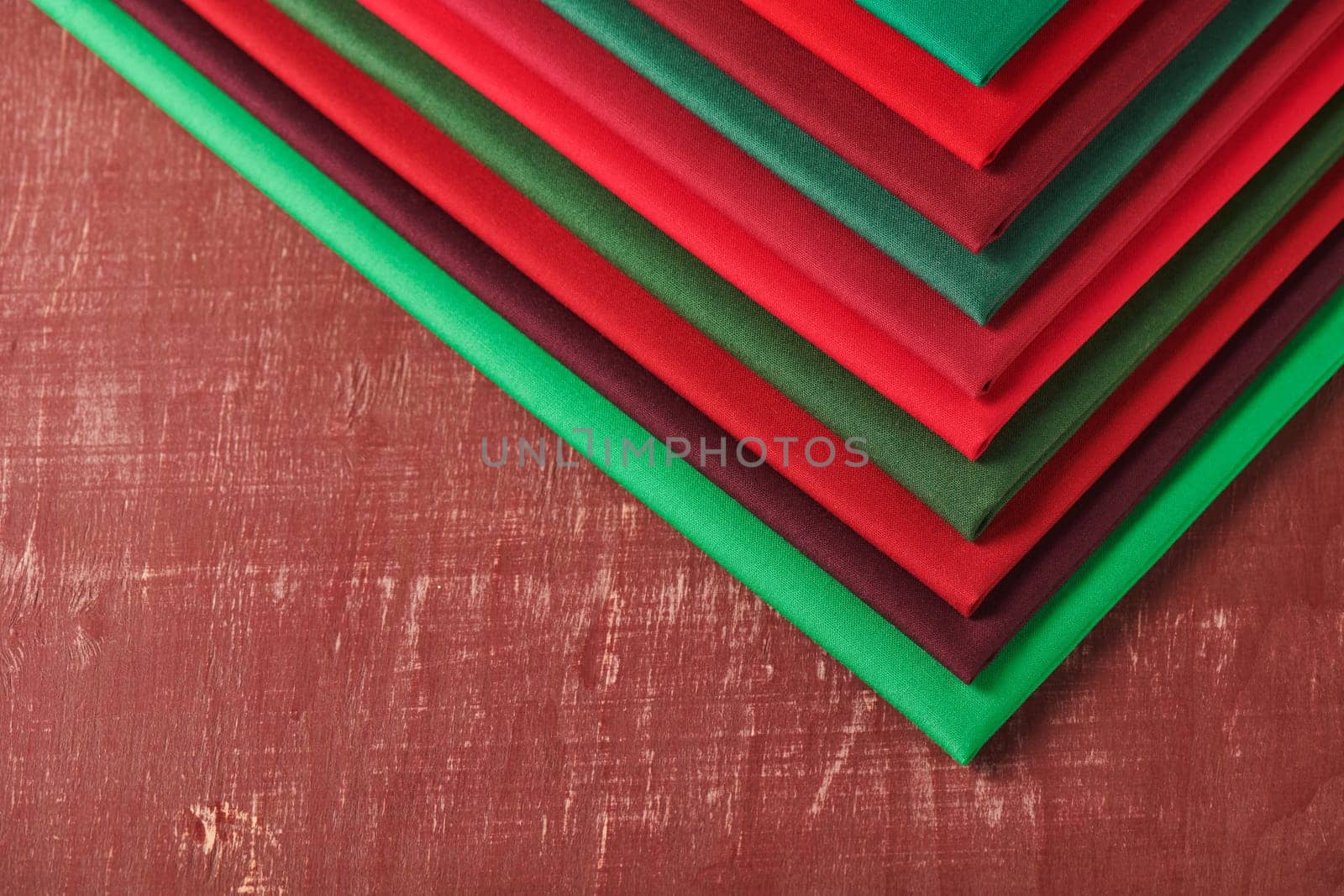 Stack of red and green fabrics on brown background, space for text