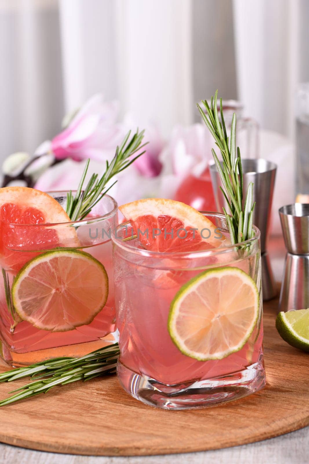 Refreshing organic cocktail with grapefruit slice, lime and rosemary sprig in a glass