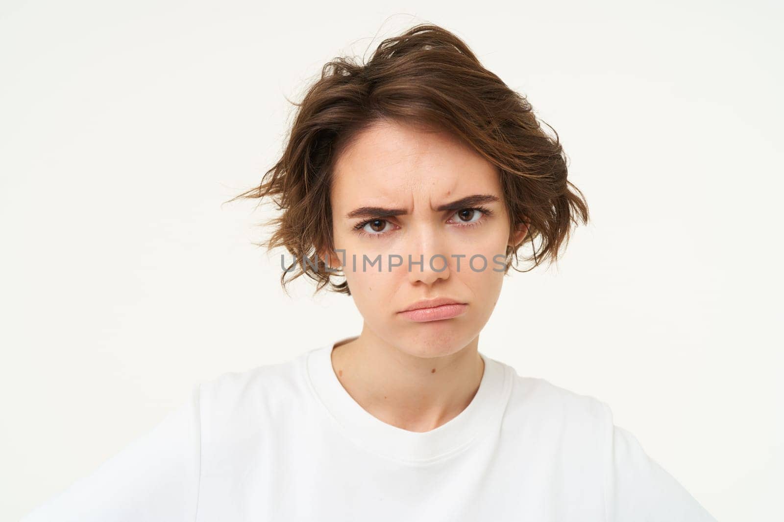 Portrait of frowning, grumpy young woman, looks upset and offended, disappointed by something, standing over white background by Benzoix