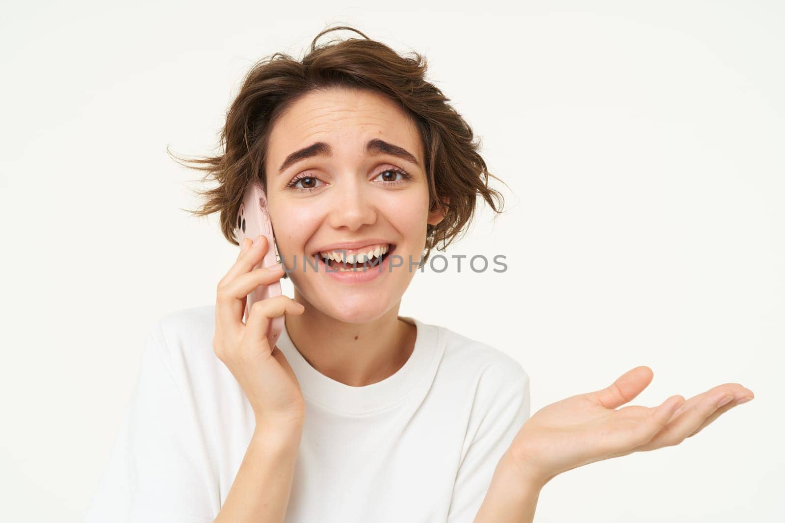 Image of smiling, brunette woman calling someone, talking on mobile phone, answer telephone call, standing over white background.