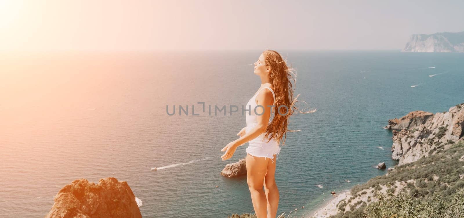 Woman travel sea. Young Happy woman in a long red dress posing on a beach near the sea on background of volcanic rocks, like in Iceland, sharing travel adventure journey