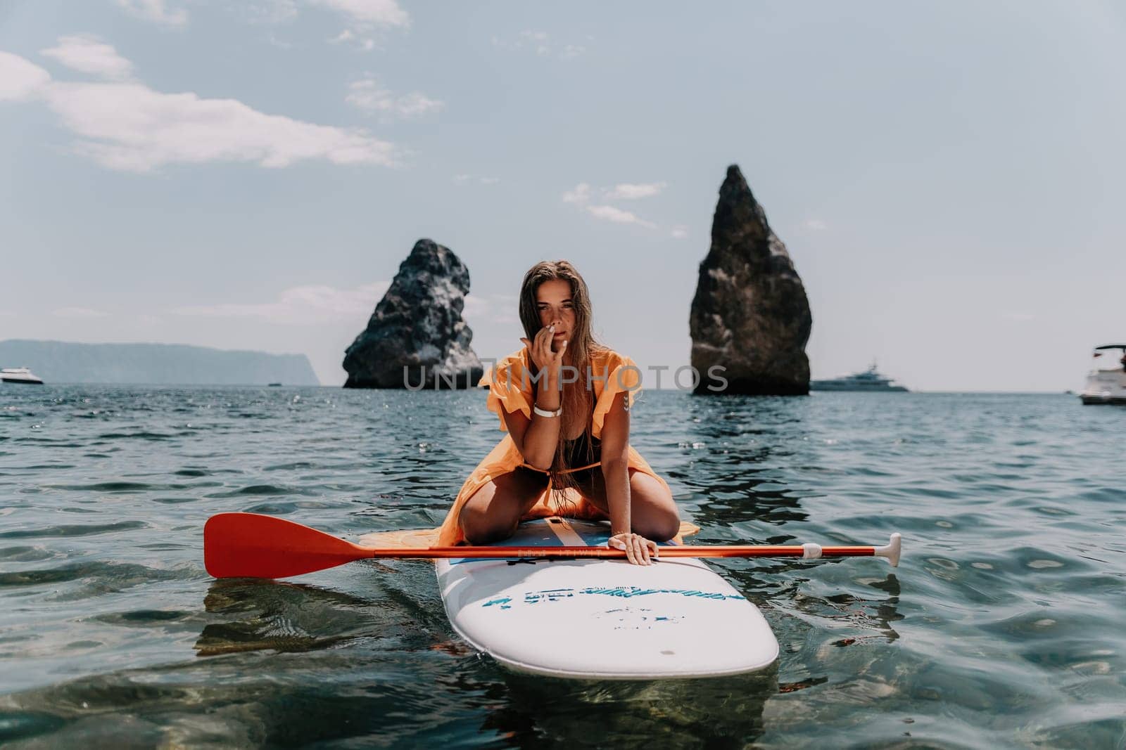 Woman sea sup. Close up portrait of happy young caucasian woman with long hair looking at camera and smiling. Cute woman portrait in bikini posing on sup board in the sea by panophotograph