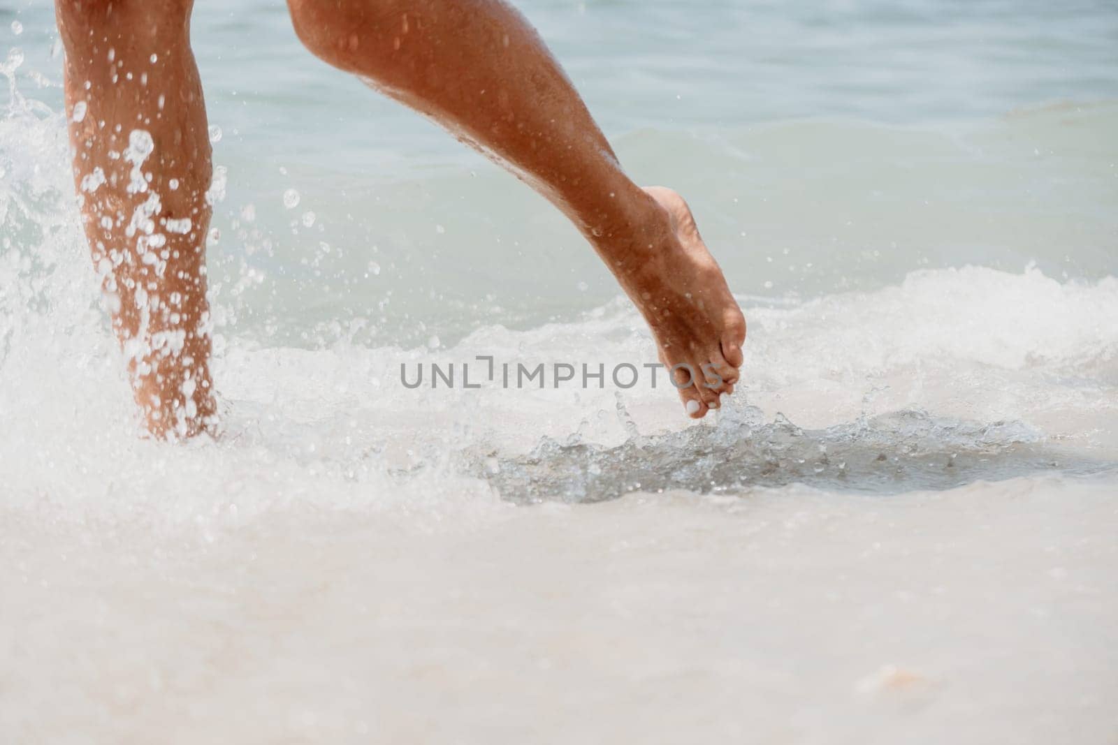 Sea beach travel - woman walking on sand beach leaving footprints in the white sand. Female legs walking along the seaside barefoot, close-up of the tanned legs of a girl coming out of the water. by panophotograph