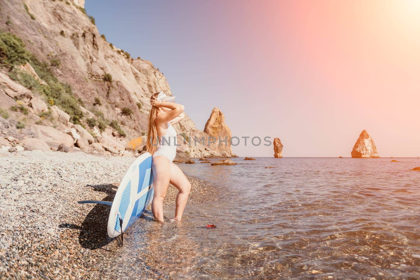 Woman sea sup. Close up portrait of happy young caucasian woman with long hair looking at camera and smiling. Cute woman portrait in a white bikini posing on sup board in the sea by panophotograph