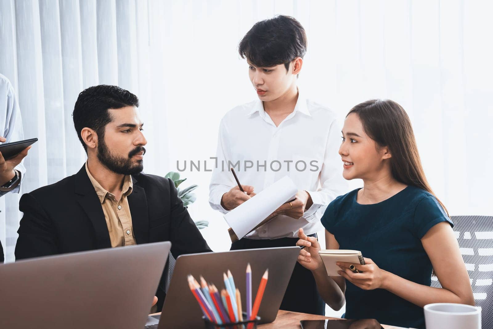 Professional Asian employee work together as team in corporate office, discussing business plans and data to achieve success on desk with laptop. Modern office worker teamwork concept. Concord