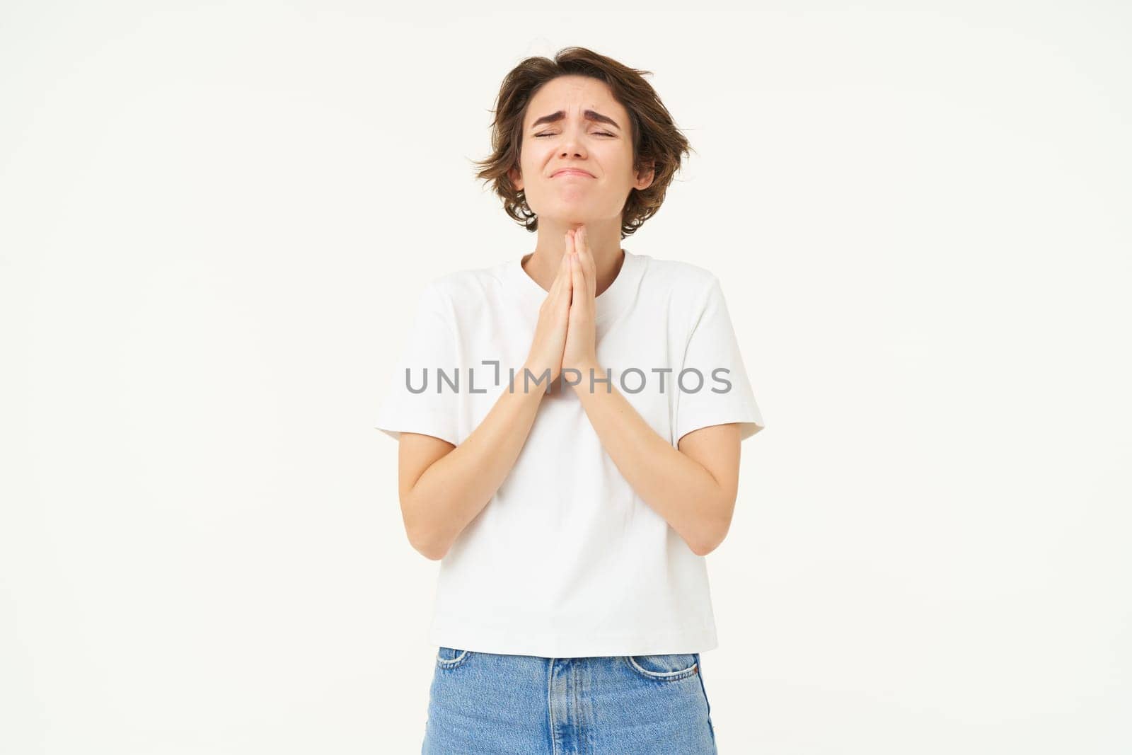 Desperate woman praying, begging for help, pleading, making wish, standing over white background.