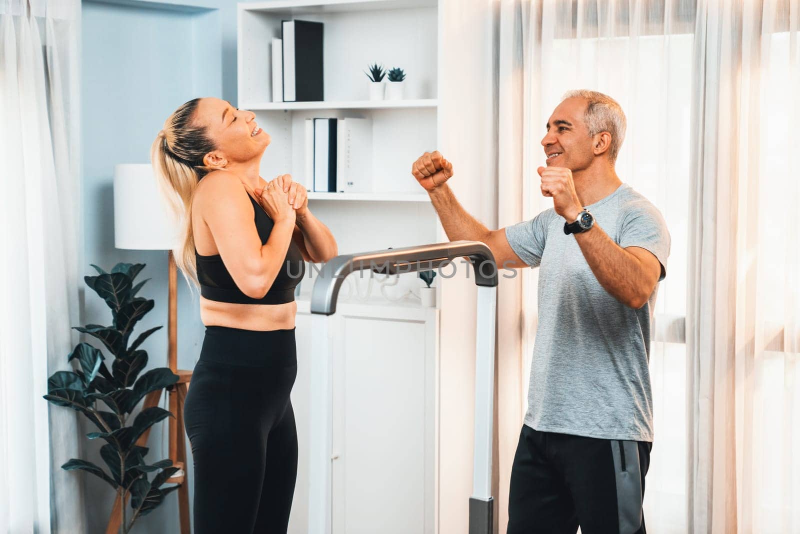 Athletic and sporty senior couple portrait in sportswear with successful or celebrating after overcome struggle posture as home exercise concept with healthy fit body lifestyle after retirement. Clout