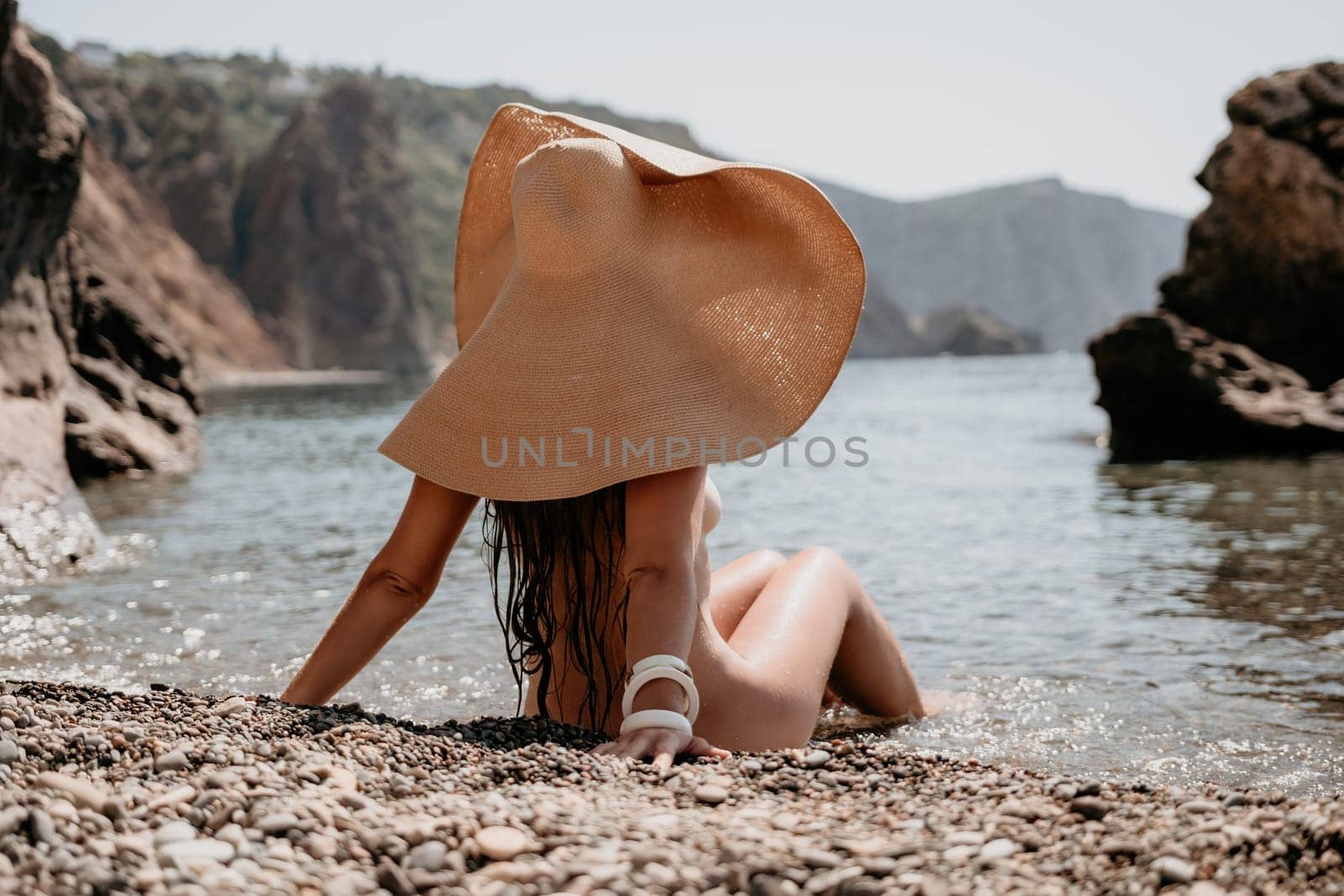 Woman travel sea. Happy tourist in hat enjoy taking picture outdoors for memories. Woman traveler posing on the beach at sea surrounded by volcanic mountains, sharing travel adventure journey by panophotograph