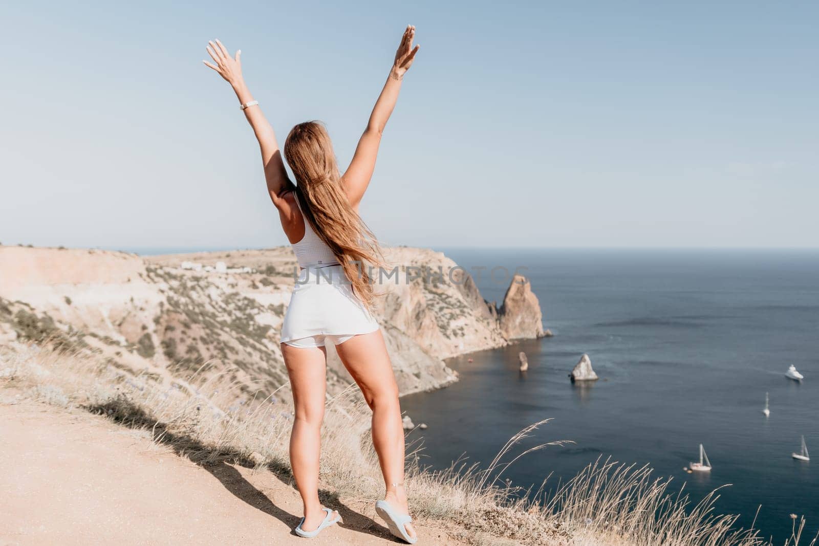 Woman summer travel sea. Happy tourist in hat enjoy taking picture outdoors for memories. Woman traveler posing on the beach at sea surrounded by volcanic mountains, sharing travel adventure journey by panophotograph